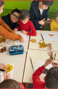 Alunni di quinta affiancano i compagni di prima durante le attività laboratoriali sull'autunno.